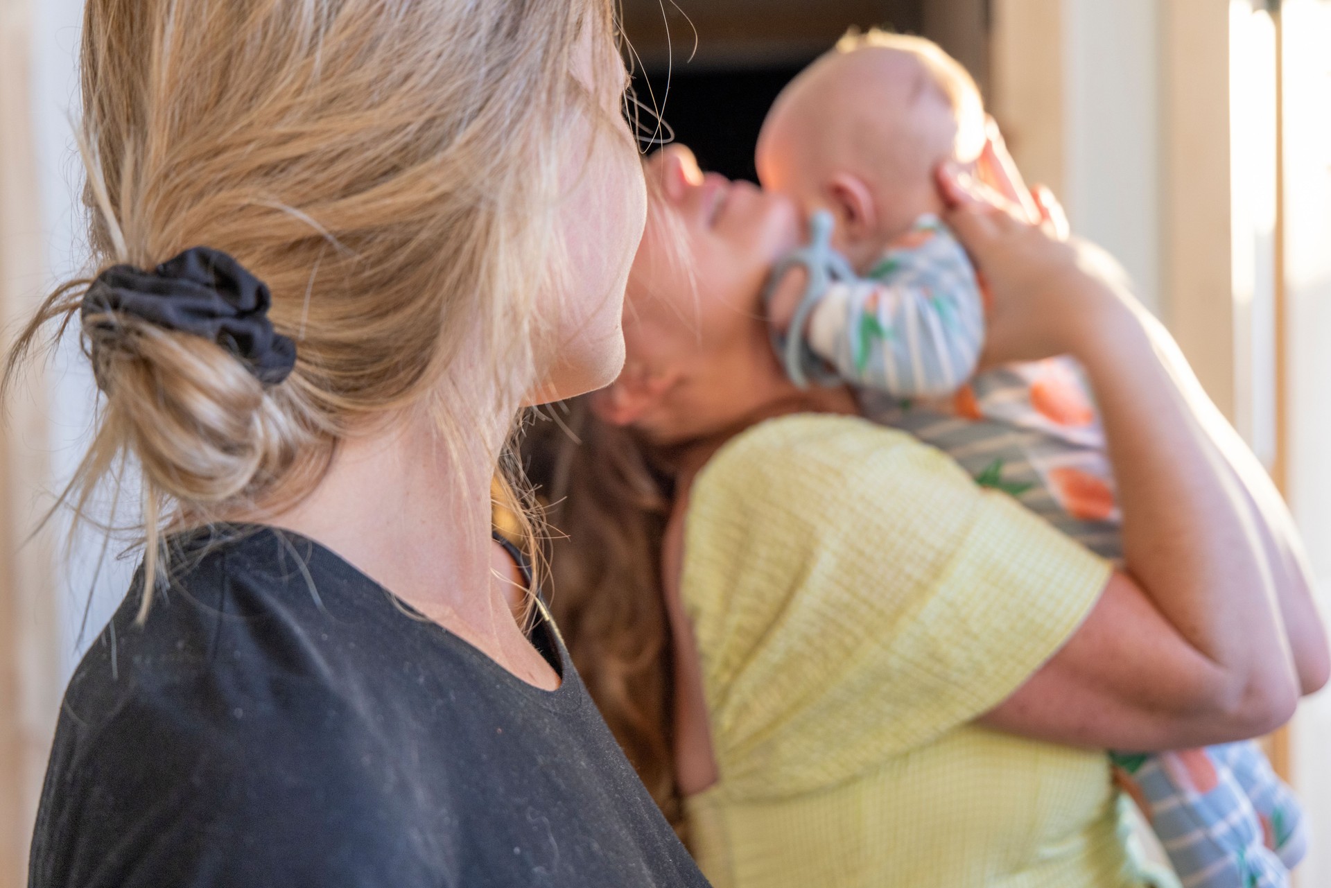 Young women play with newborn baby